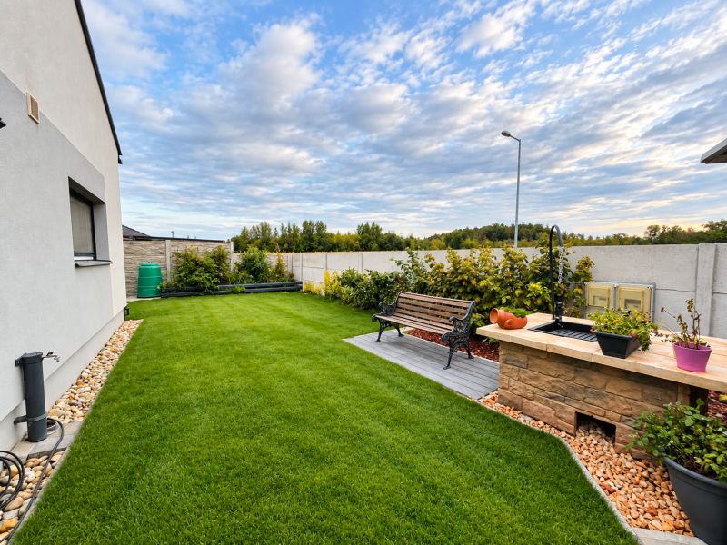 The garden of a family house in Mosonmagyaróvár with a bench and an outdoor grill on the lawn.