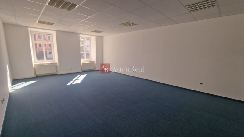 Spacious offices with blue carpet and ceiling lights.