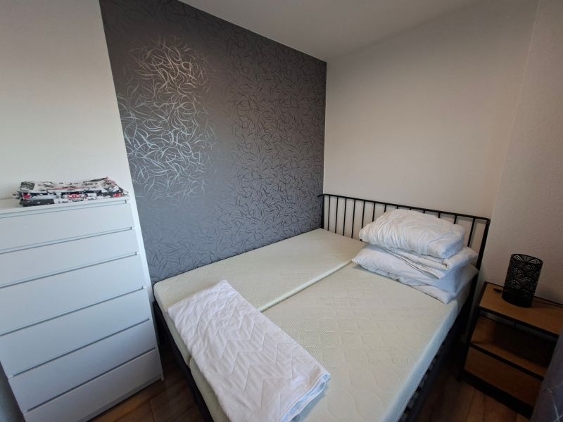 A bedroom in a studio apartment with a dark wall and a wooden decor floor.