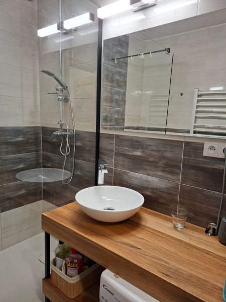 Bathroom in a studio apartment with a sink and shower, floor with wood decor.