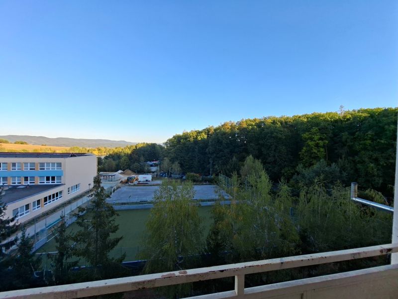 View from a one-room apartment on Školská Street in Kanianka with forests and a school.