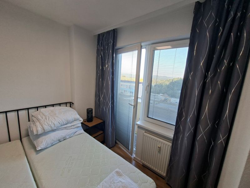 Bedroom space in a studio apartment with curtains and a window with a view.