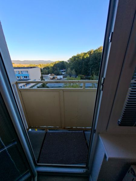 View from the balcony of a one-room apartment on Školská Street in Kanianka with a forest backdrop.