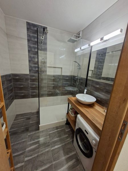 Bathroom in a studio apartment with a sink, shower, and washing machine.
