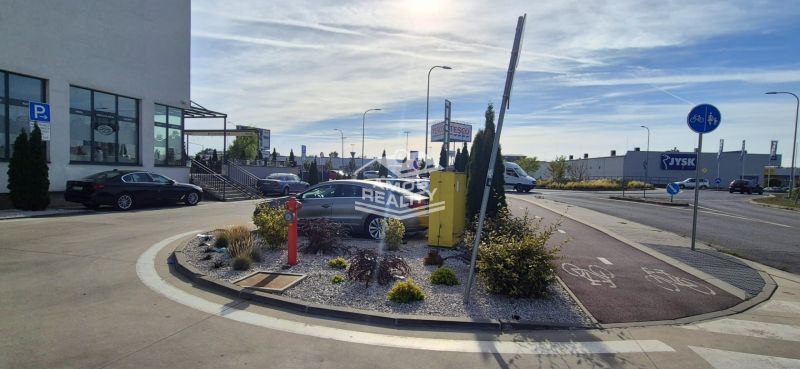Javorová Street in Malacky, shops like Tesco and Jysk, parking lot and bike path.
