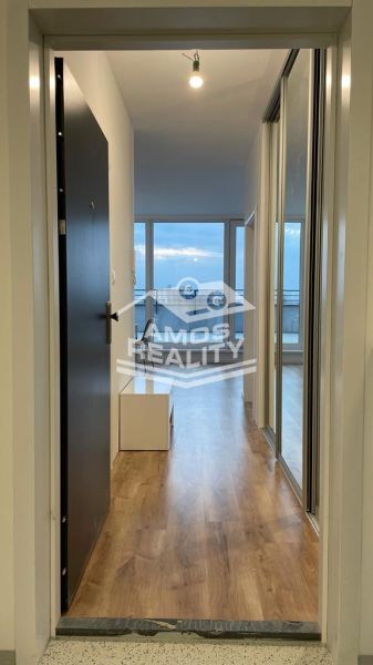 Entrance hallway in a 2-room apartment with a wooden decor floor and large windows.