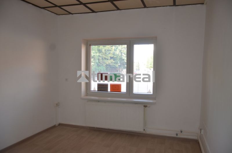 Offices with white walls and a floor with a wooden decor, a window with a radiator is visible.