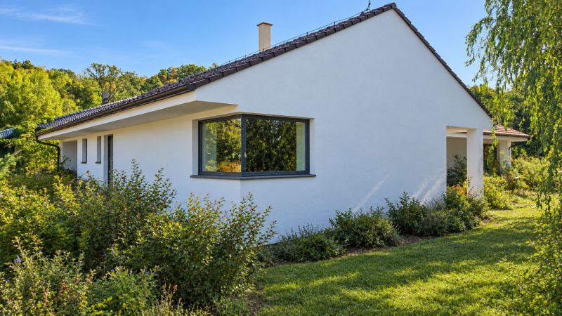 A family house in Ratnovce surrounded by greenery, with large windows and a simple white facade.