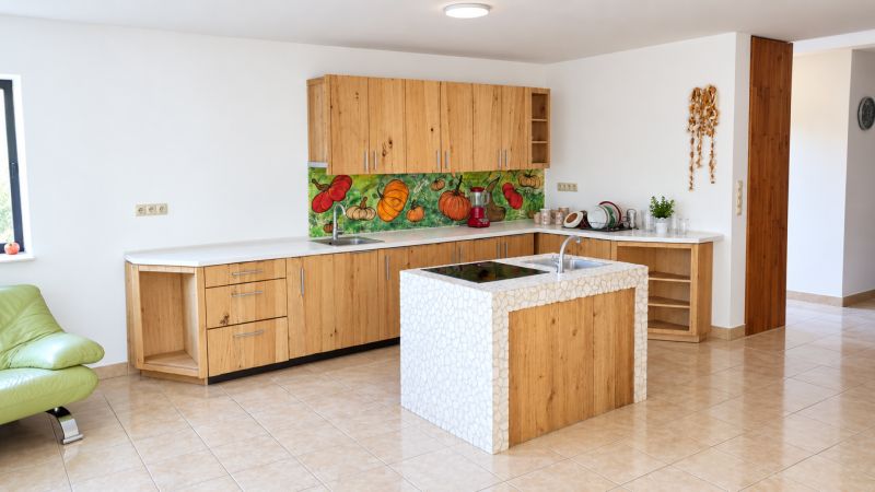 A kitchen in a family house with a kitchen unit and a colorful vegetable backsplash.