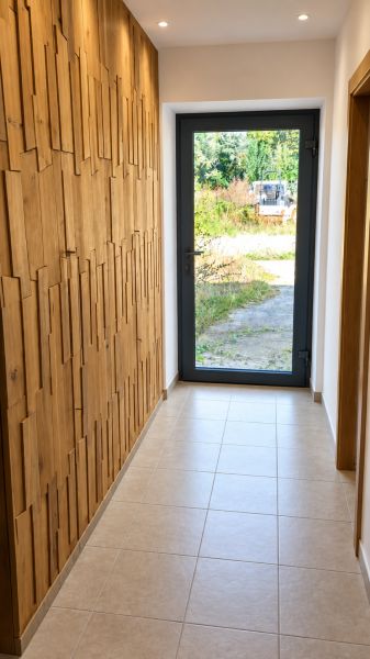 A hallway in a family house with wooden elements on the wall and glass doors.