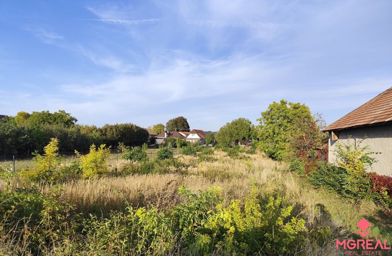Plots - housing in Jasová, surrounded by greenery with visible buildings in the background.