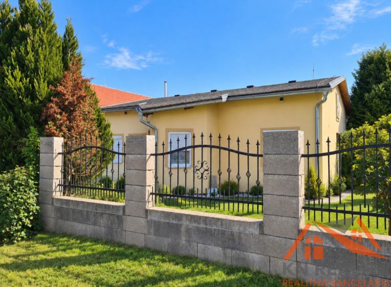 A family house in Martovce with a garden surrounded by green trees and a fence.
