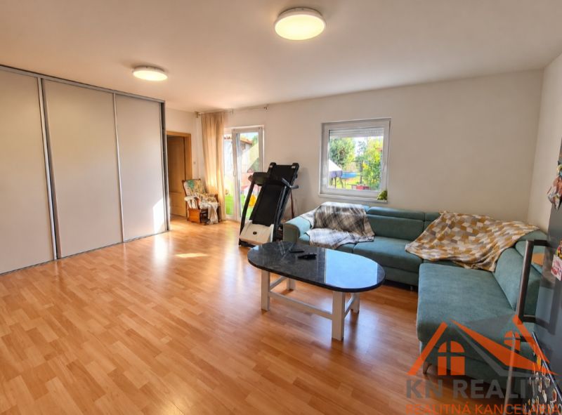 Living room in a family house with a wooden decor floor and a green sofa.
