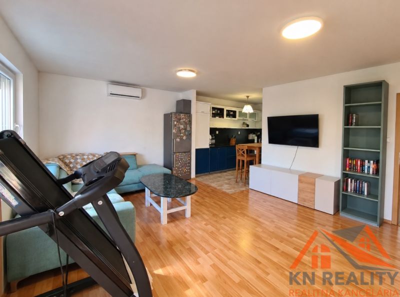 Living room in a family house with wood-patterned flooring, a sofa, and a television.