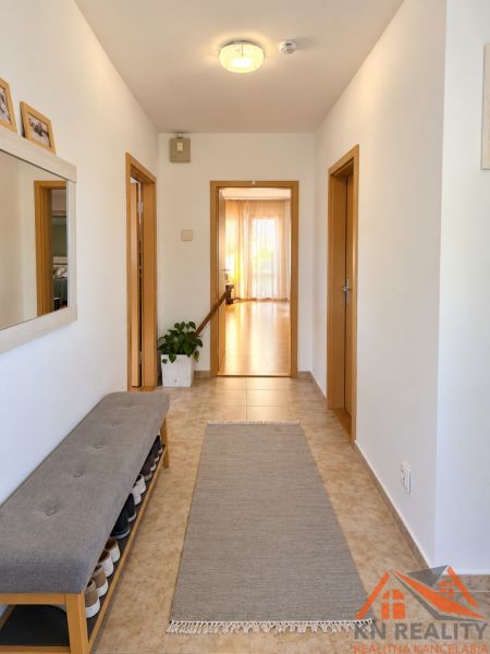 Hallway in a family house with tiles, a shoe bench, and a mirror.