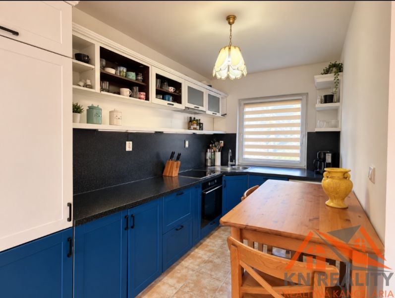 A kitchen in a family house with stylish blue cabinets and a cozy wooden table.