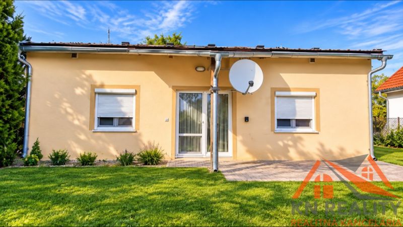 A family house in Martovce with white windows, a satellite dish, and a manicured lawn.