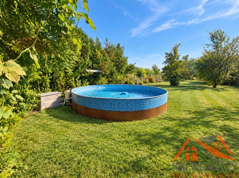 Outside in Martovce near a family house, a round pool on the lawn surrounded by greenery.