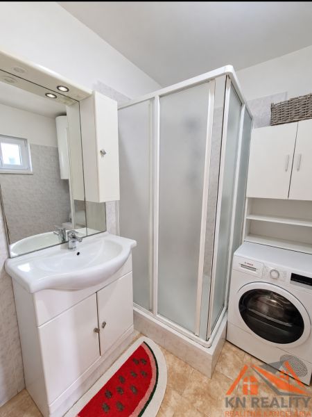 A bathroom in a family house with a sink, shower, and washing machine.