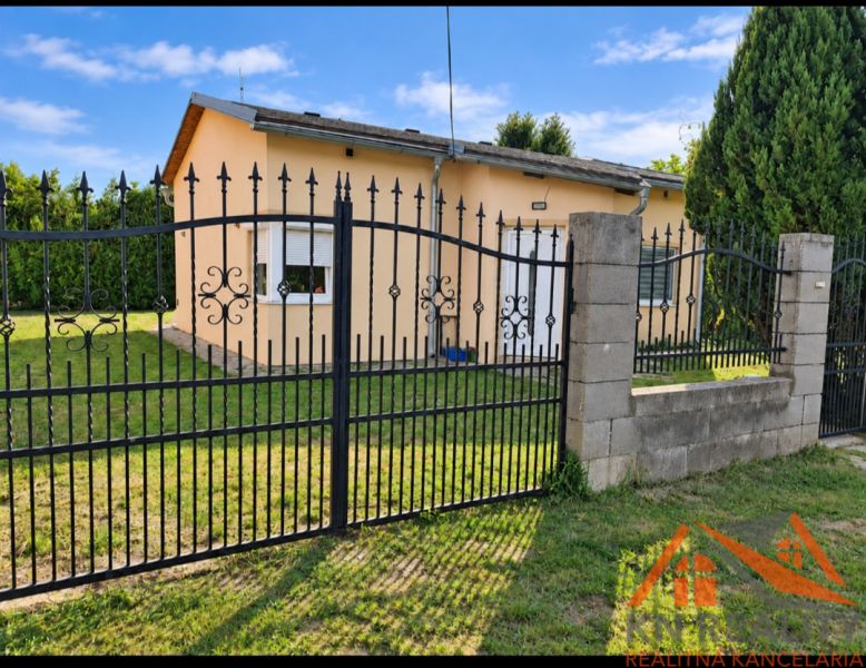 A family house in Martovce with a grassy plot and a metal fence.