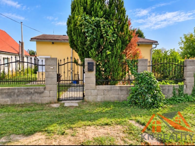 A family house in Martovce with a front garden and a metal gate, surrounded by a hedge.