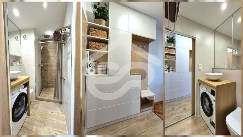 Cozy bathroom with wood-patterned flooring, a shower, a washing machine, and storage space.
