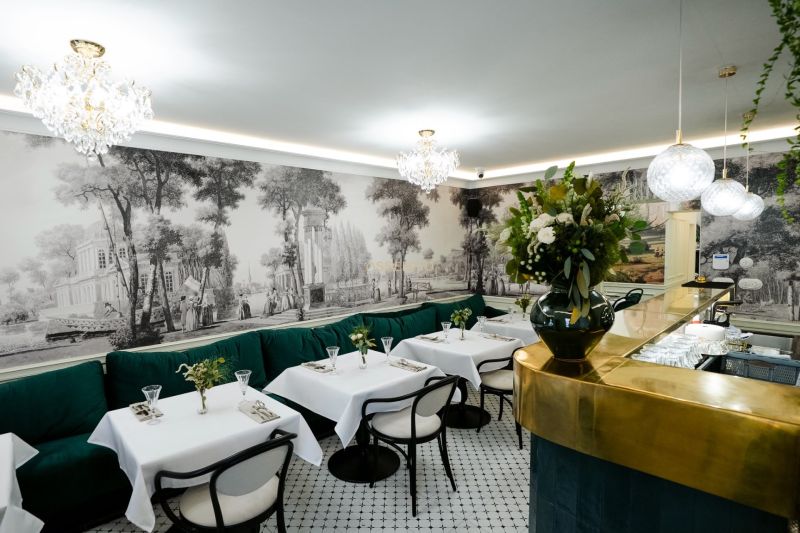 Interior of commercial spaces with white tables, green sofas, and wall paintings.