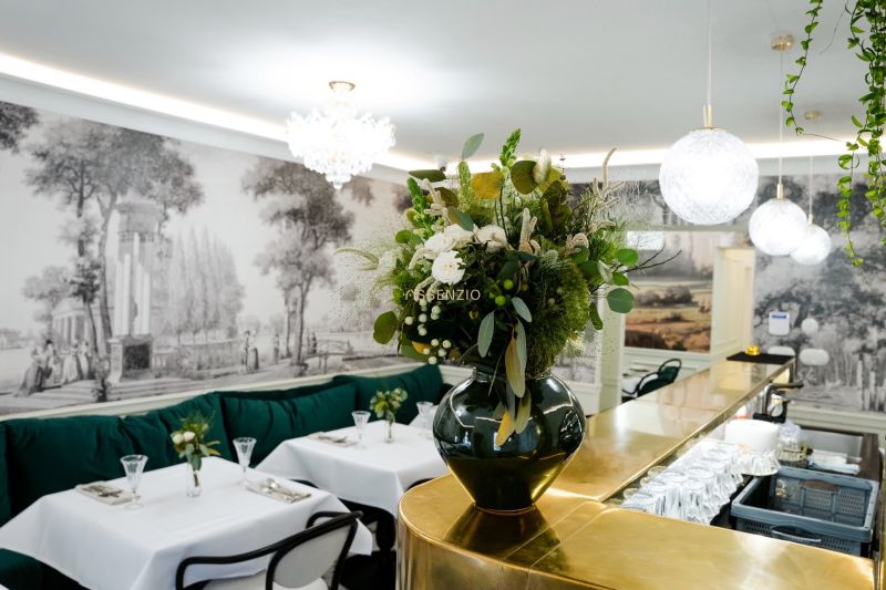 Interior of commercial spaces with a golden bar, floral decoration, and elegant tables.