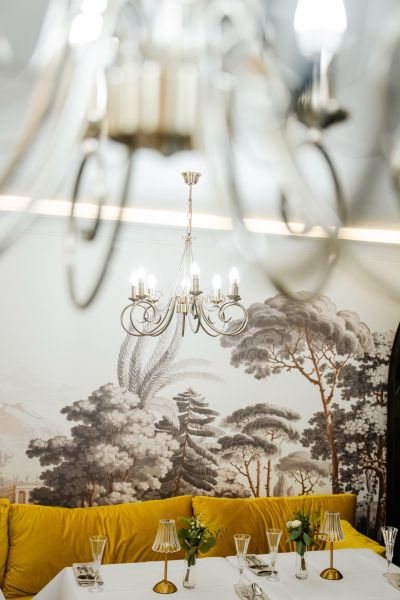 A stylish chandelier illuminates a table decorated with golden hues in commercial premises.