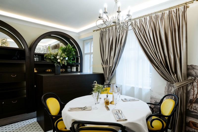 A dining area in commercial premises with elegant curtains and a table with yellow chairs.