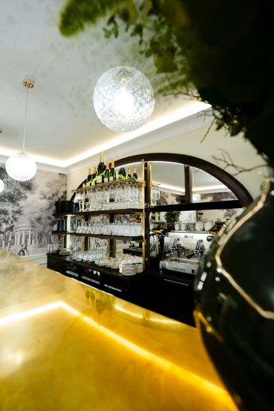 Commercial space with a bar counter, shelves with glasses, and a coffee machine.