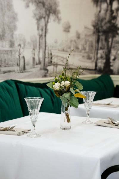 An elegantly set table with a white tablecloth, a vase with flowers, and crystal glasses.
