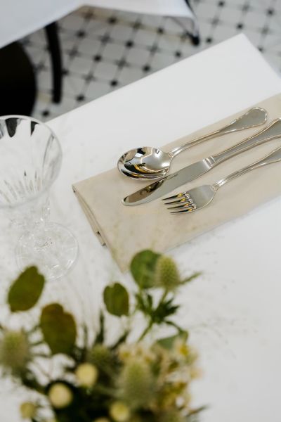 A table set with cutlery and a glass, decorated with flowers on the table.