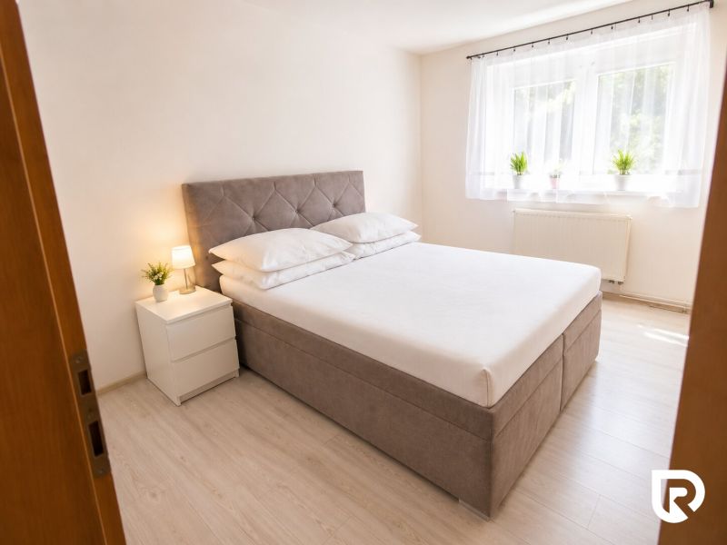 A bedroom with a bed, nightstands, and a floor with a wooden decor in a two-room apartment.