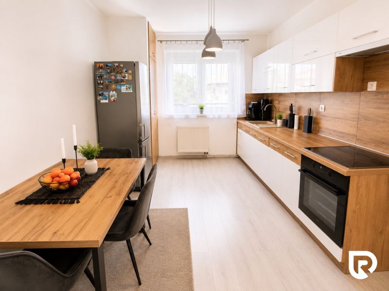 A kitchen in a 2-room apartment with a wooden decor floor, a dining table, and appliances.