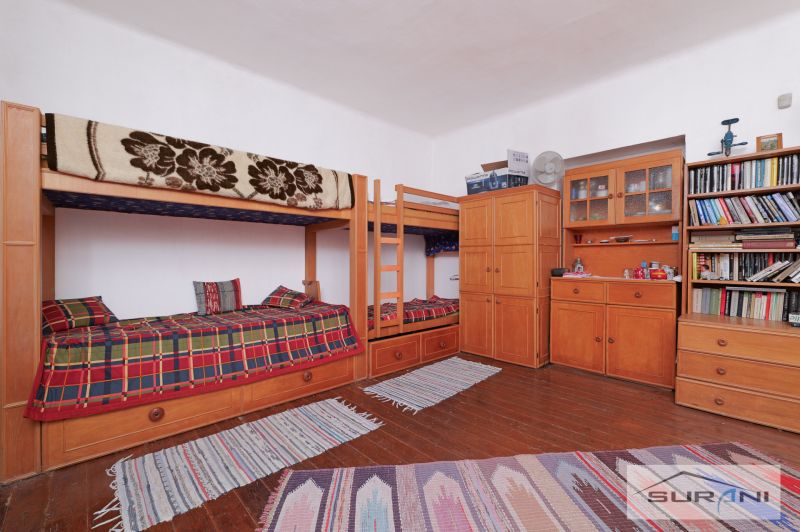 Interior of a family house with a bunk bed, dressers, and a floor with a wooden decor.