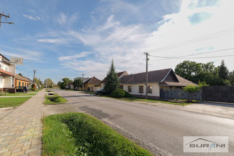Family houses on Hlavná Street in Štefanová with landscaped gardens and a clear sky.