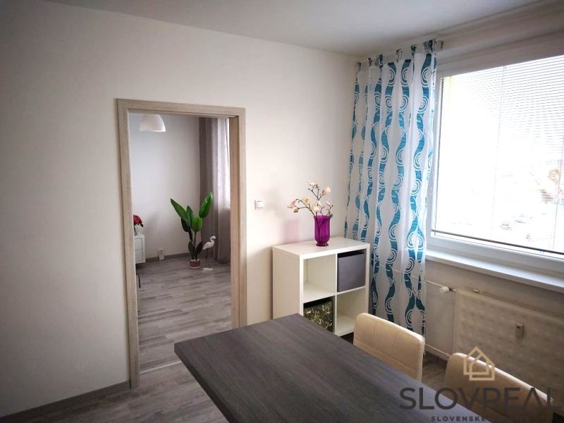 Interior of a 1-room apartment with a wooden decor floor, colorful curtains, and decorations.