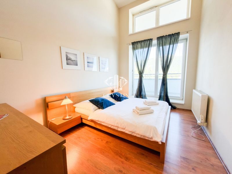A bedroom in a 3-room apartment with a wooden decor floor and large windows.