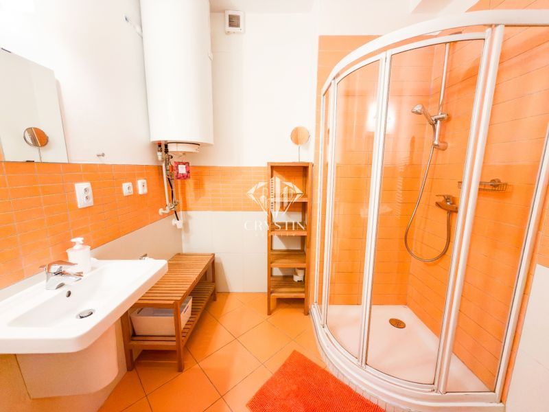 A bathroom in a 3-room apartment with orange tiles, a shower corner, and a white sink.