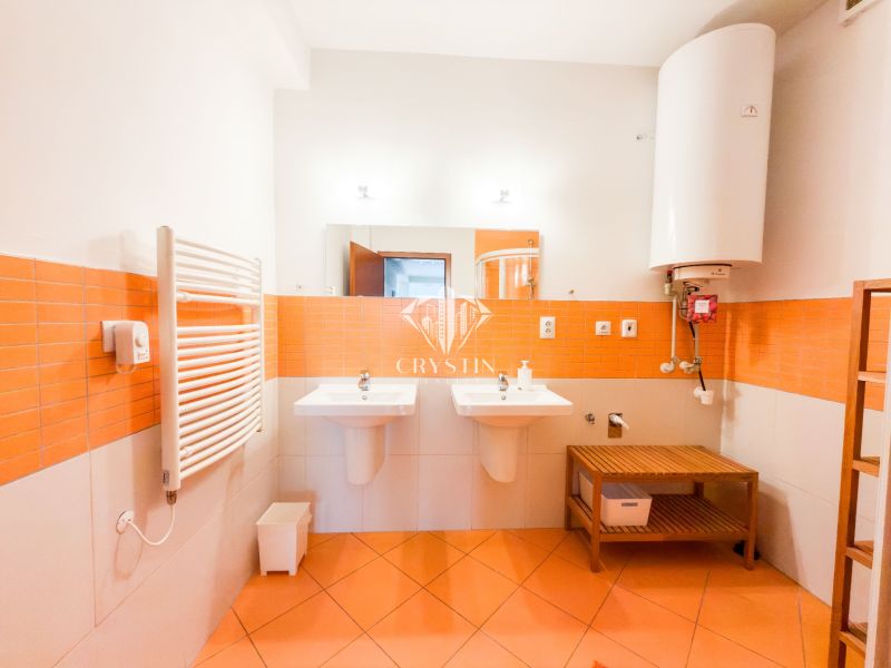 A bathroom in a 3-room apartment with orange tiles, two sinks, and a boiler.