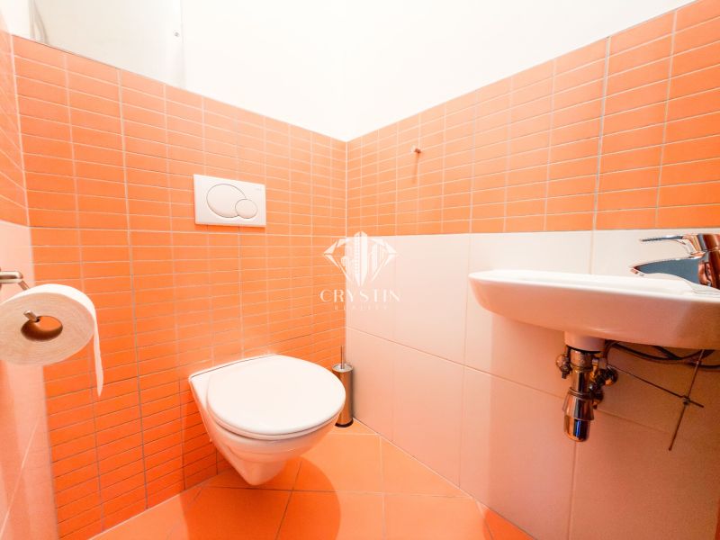 A bathroom in a 3-room apartment with orange tiles and a wall-hung toilet.