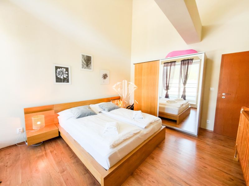 Bedroom with a bed and a large wardrobe, set on a floor with a wooden decor.