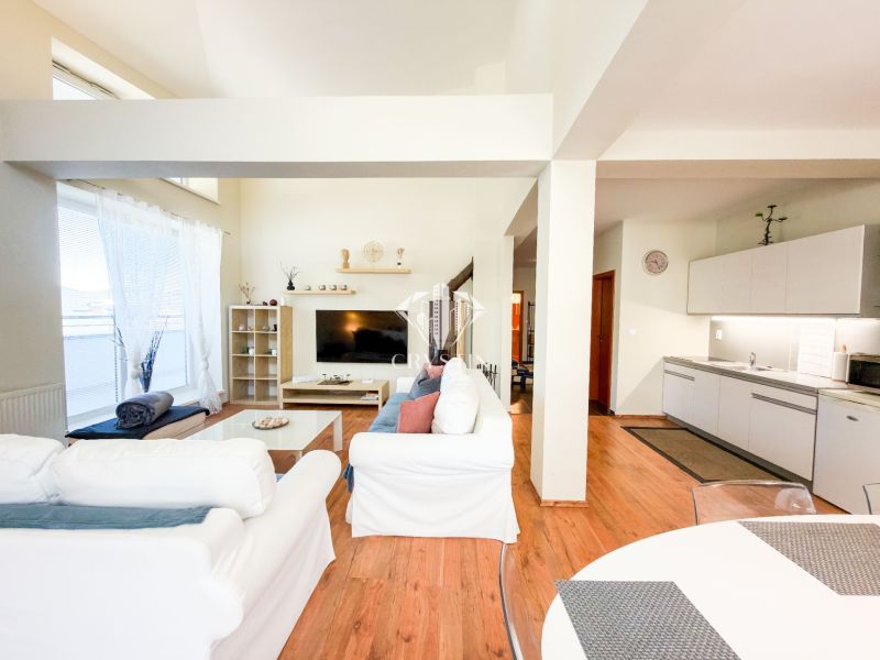 Living room with wood-patterned flooring in a 3-room apartment, light furnishings, kitchenette.