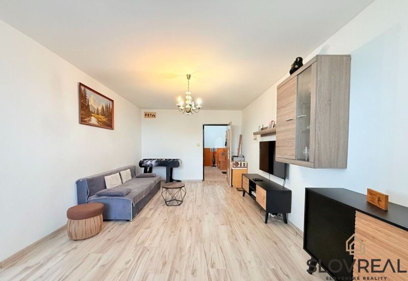 Living room in a 3-room apartment with a wood-patterned floor, gray sofa, and foosball table.