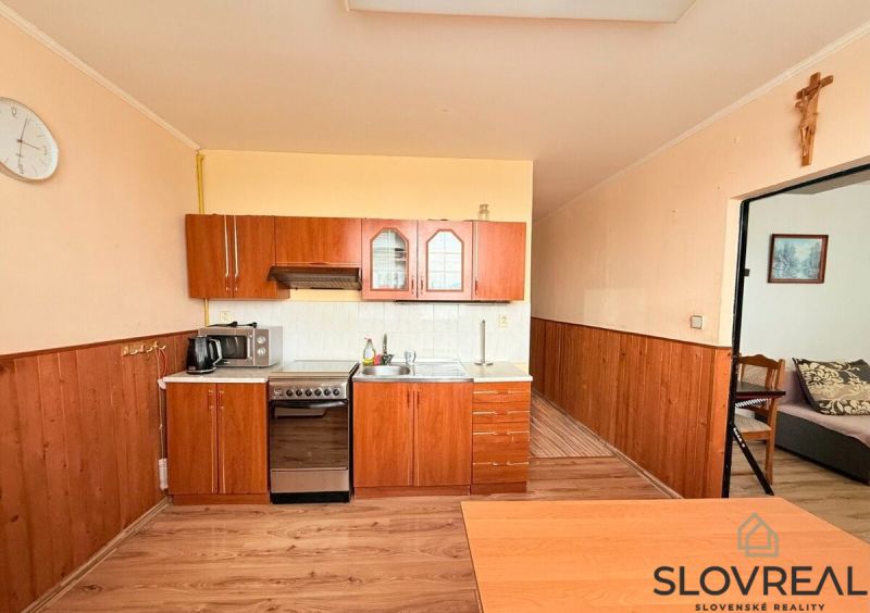 A kitchen in a 3-room apartment with a wooden decor floor and a kitchen unit.