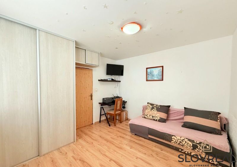Living room in a 3-room apartment with a wooden decor floor, a sofa, and a cabinet.
