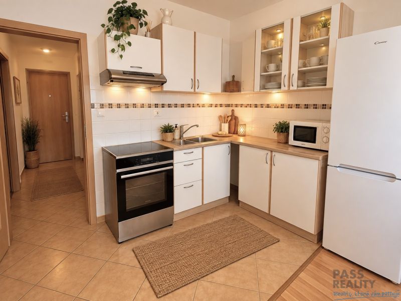 A kitchen with white cabinets and appliances in a two-room apartment.