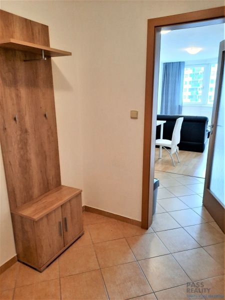 The entrance hall in a 2-room apartment with a coat rack and a view into the living room with a dining area.