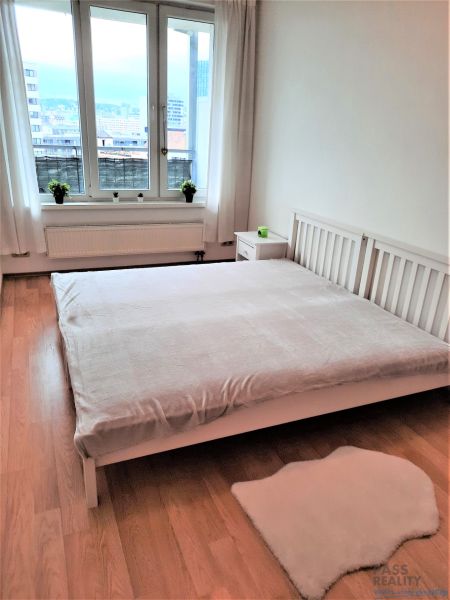 A bright bedroom in a two-room apartment with a window and a wooden decor floor.
